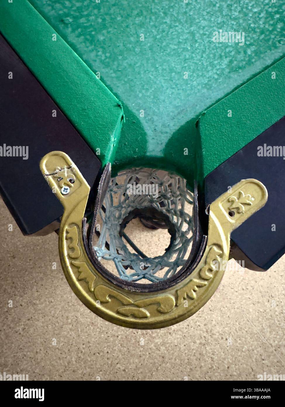 Un coin d'une vieille table de billard avec une vue de dessus de la poche et une partie de la table recouverte de tissu vert. Banque D'Images