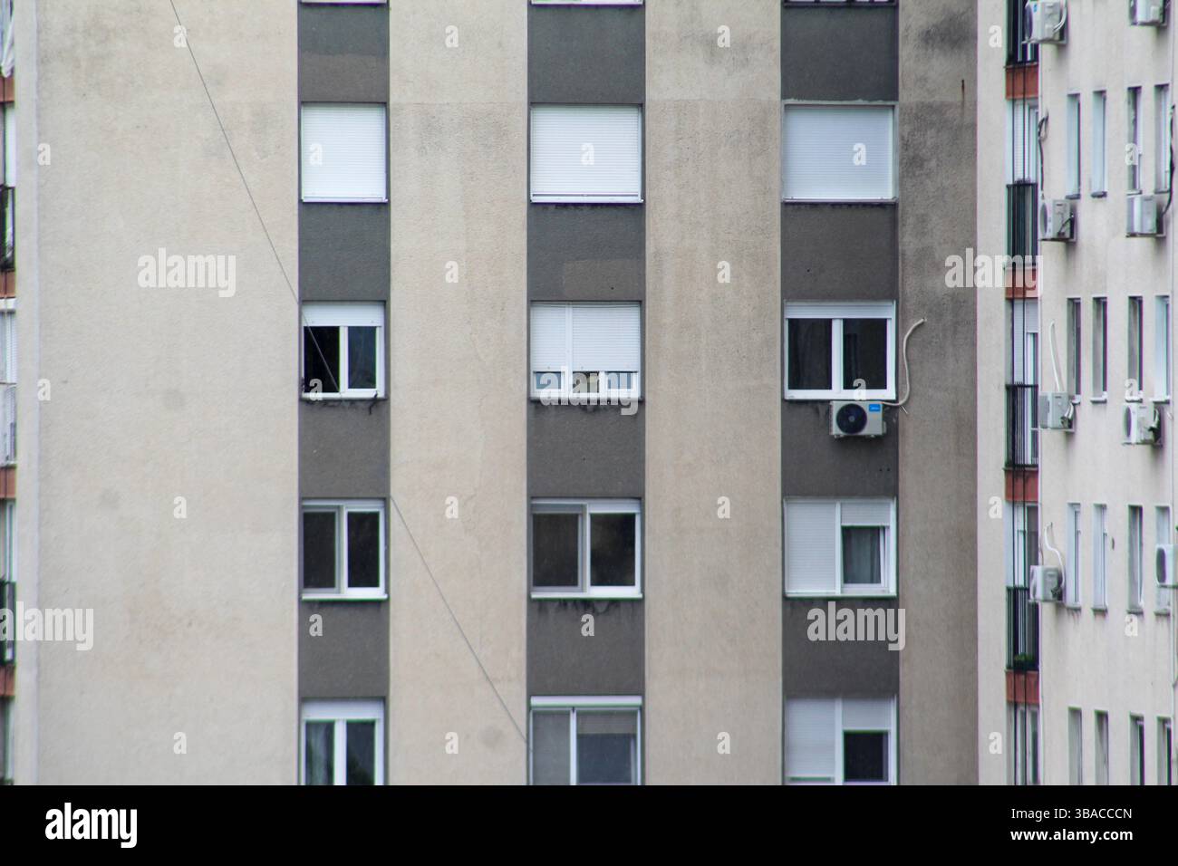 Vue rapprochée d'une façade de bâtiment de grande hauteur montrant des fenêtres, des stores fermés et des climatiseurs montés. Banque D'Images