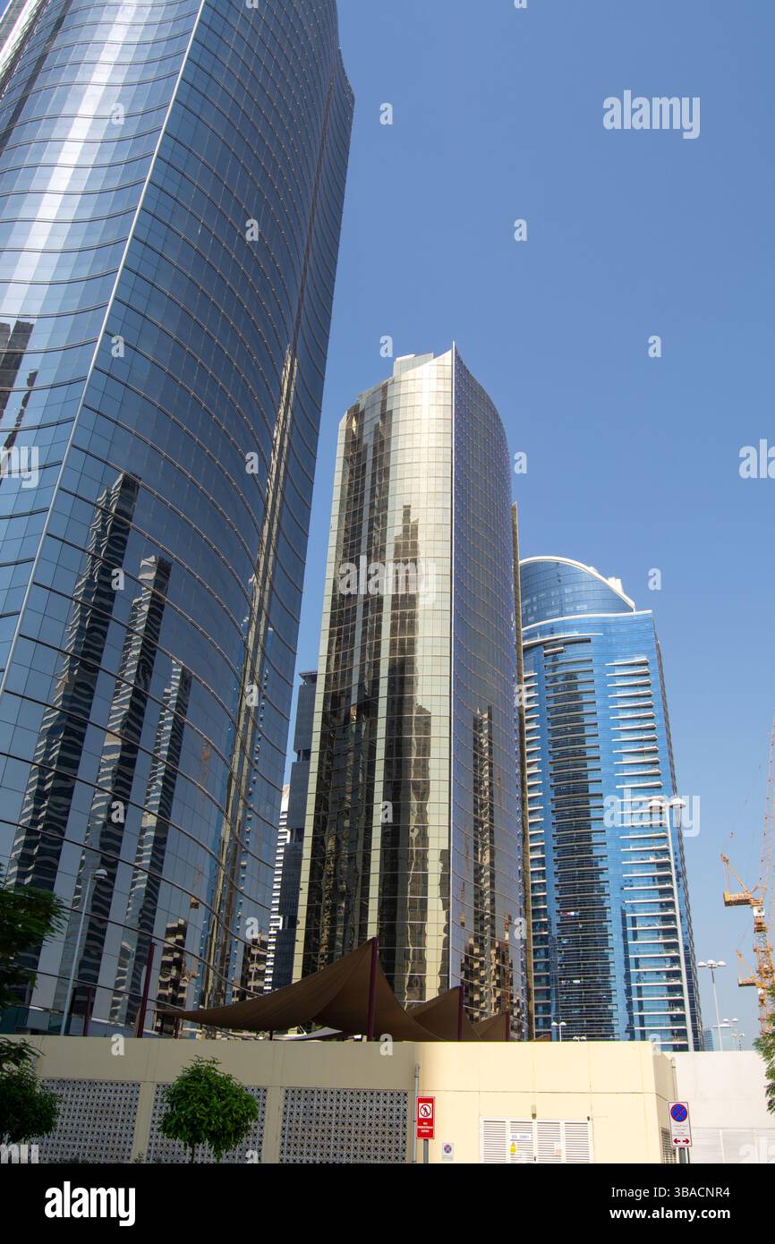 Une vue des gratte-ciel modernes avec des façades en verre réfléchissantes sous un ciel bleu clair. Les bâtiments présentent un mélange de conceptions courbes et angulaires, avec sh Banque D'Images