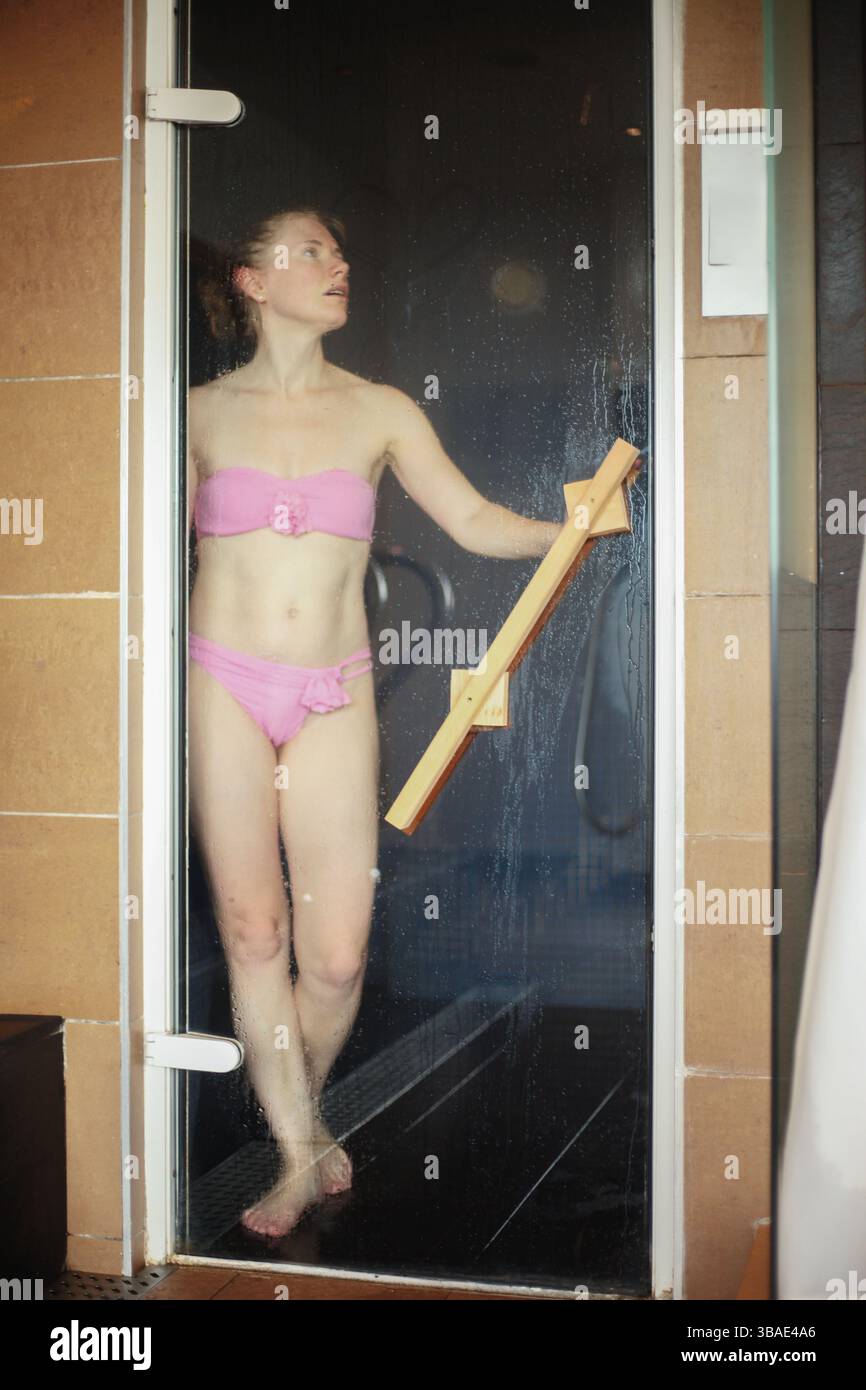 Femme en bikini profitant de la thérapie thermique dans le sauna à vapeur moderne. Banque D'Images