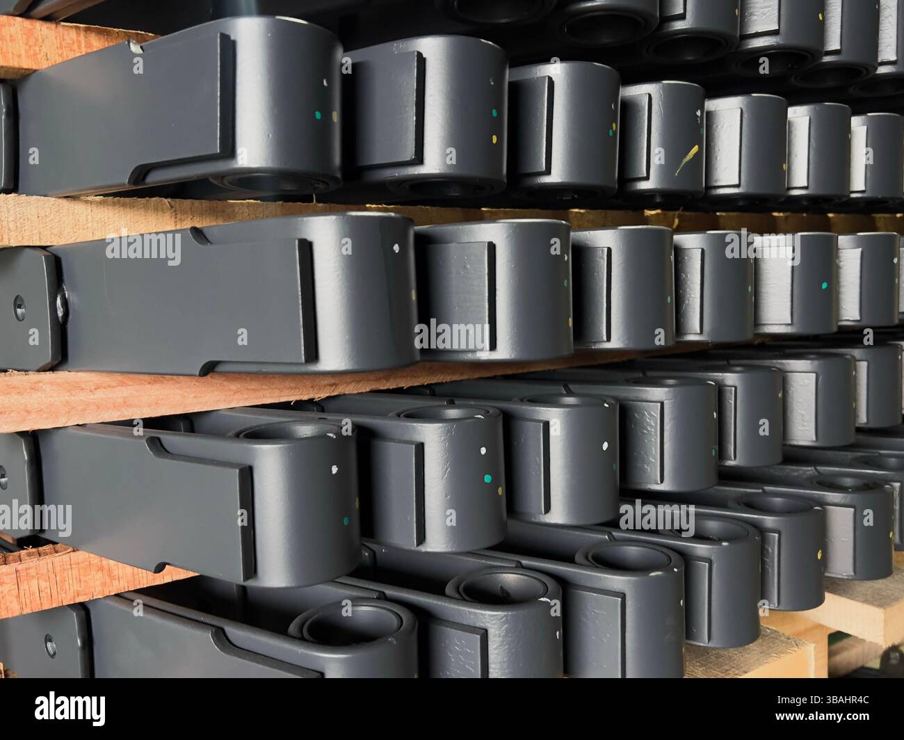 Gros plan de ressorts à lames noirs soigneusement empilés sur des palettes en bois dans un entrepôt. - Image de stock capturée avec un smartphone