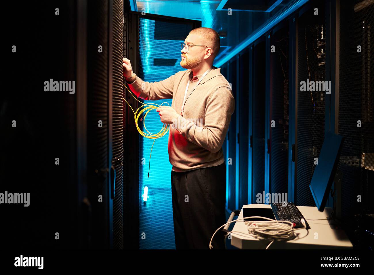 Technicien connectant les câbles réseau dans la salle des serveurs Banque D'Images