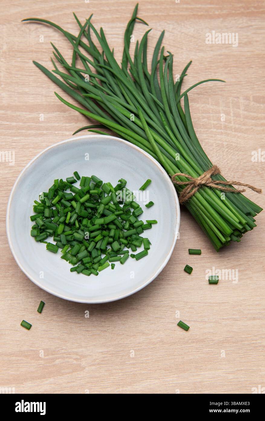 Ciboulette fraîche groupée et hachée dans un bol sur une surface en bois Banque D'Images