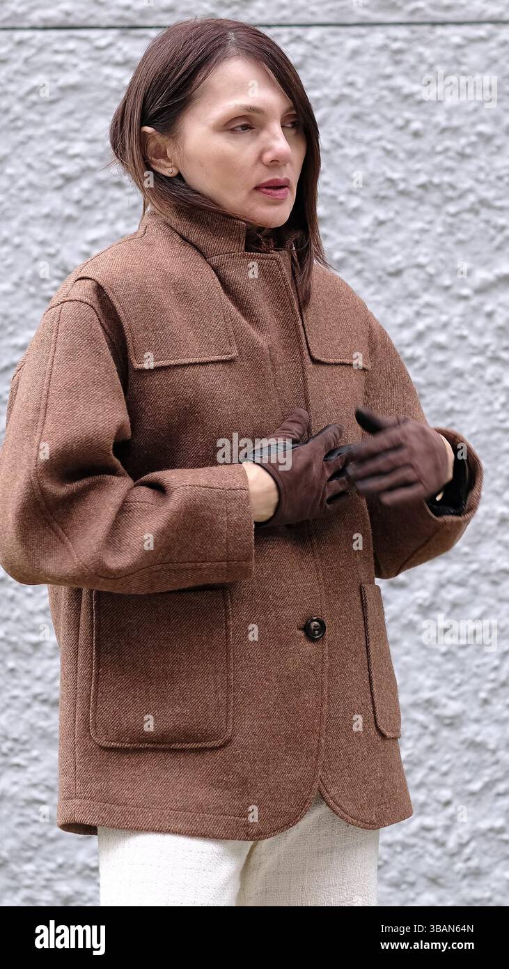 Une femme d'âge moyen vêtue d'un manteau chaud se protégeant du froid. Ce moment reflète la chaleur et le stress associés aux changements de vie comme la ménopause Banque D'Images