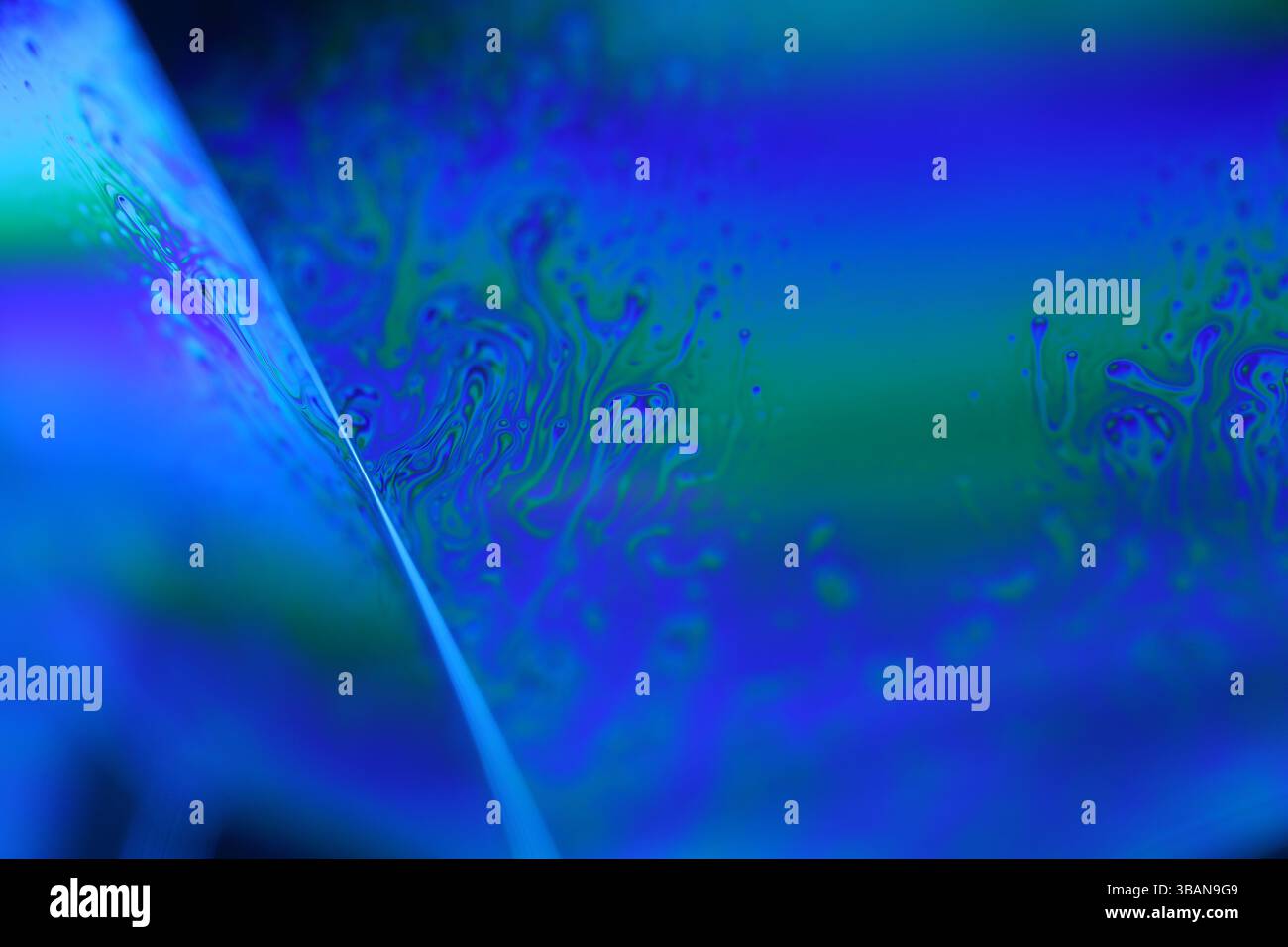 Surface liquide bleu profond sur fond noir, mouvement des taches d'huile, chimie brillante, fond surréaliste, couleur bleu ciel Banque D'Images