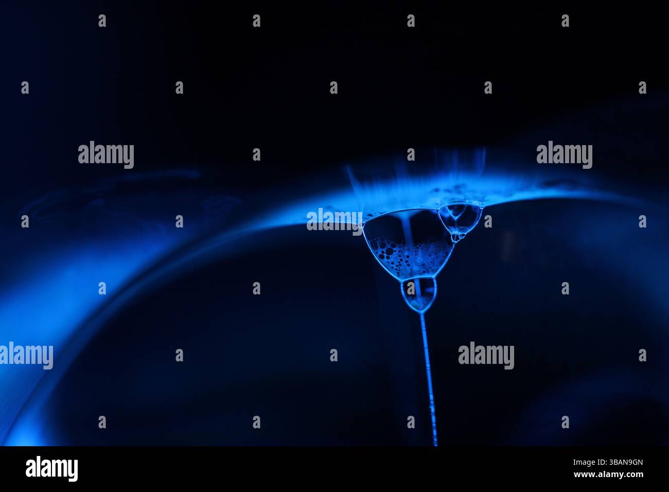 Surface liquide bleu profond sur fond noir, mouvement des taches d'huile, chimie brillante, fond surréaliste, couleur bleu ciel Banque D'Images