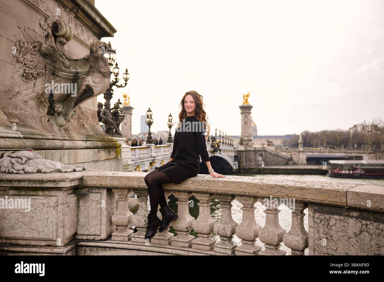 Femme assise sur la balustrade en pierre du pont historique.05.04.2025 Paris France Banque D'Images