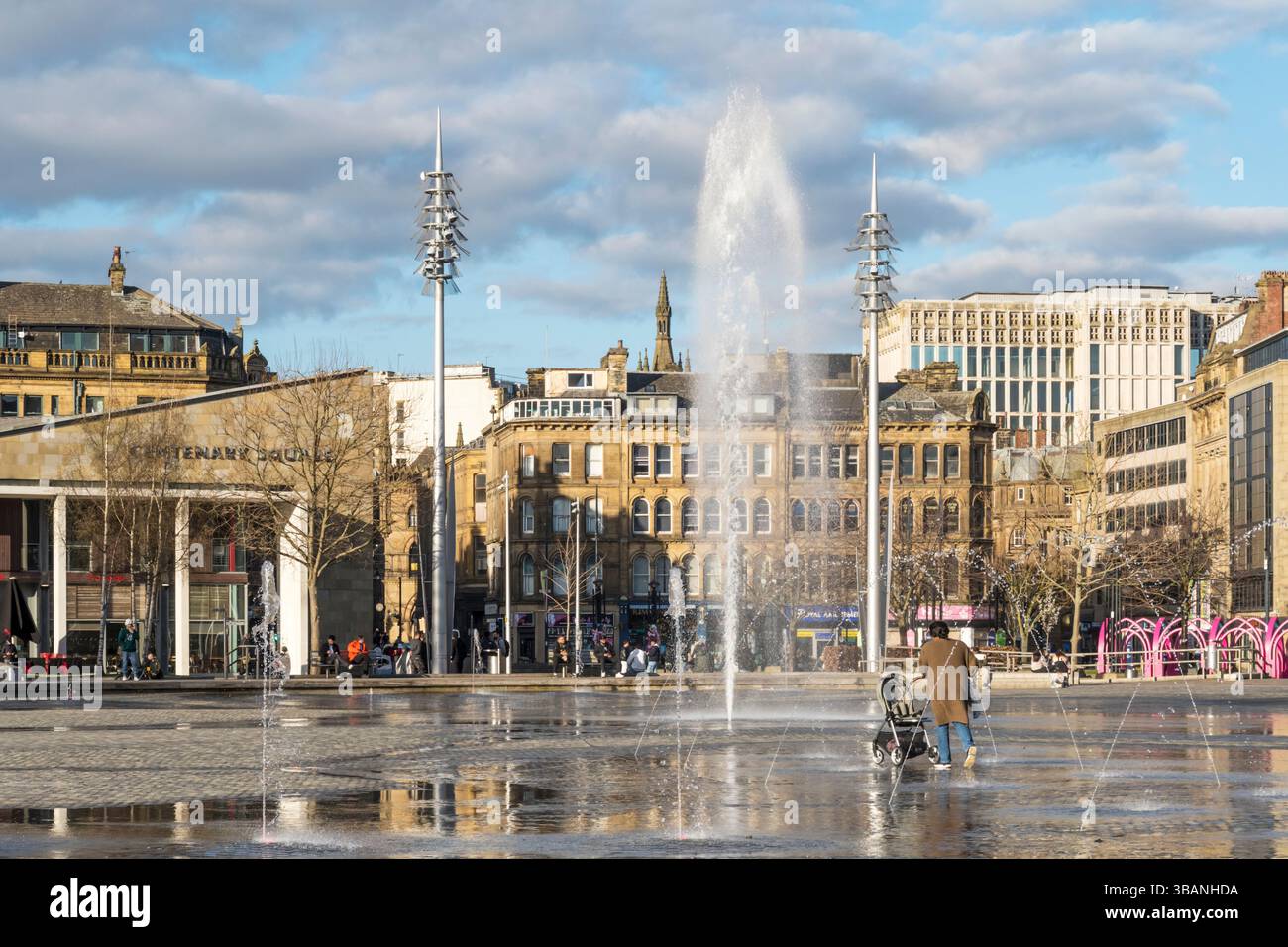 Les gens marchent à travers les fontaines de Centenary Square dans le centre de Bradford. Banque D'Images