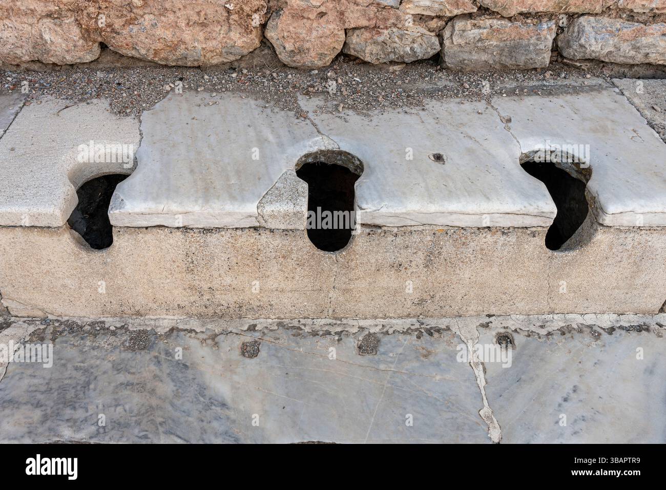 Rangée de toilettes romaines en pierre à Éphèse, avec des sièges en forme de trou de serrure utilisés communalement, une partie des anciens systèmes d'assainissement public. Banque D'Images