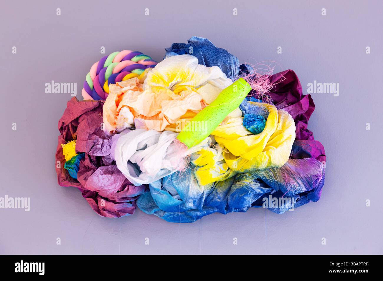 Motif multicolore coloré sur un mur violet fabriqué à partir de divers produits en papier et en plastique. Banque D'Images