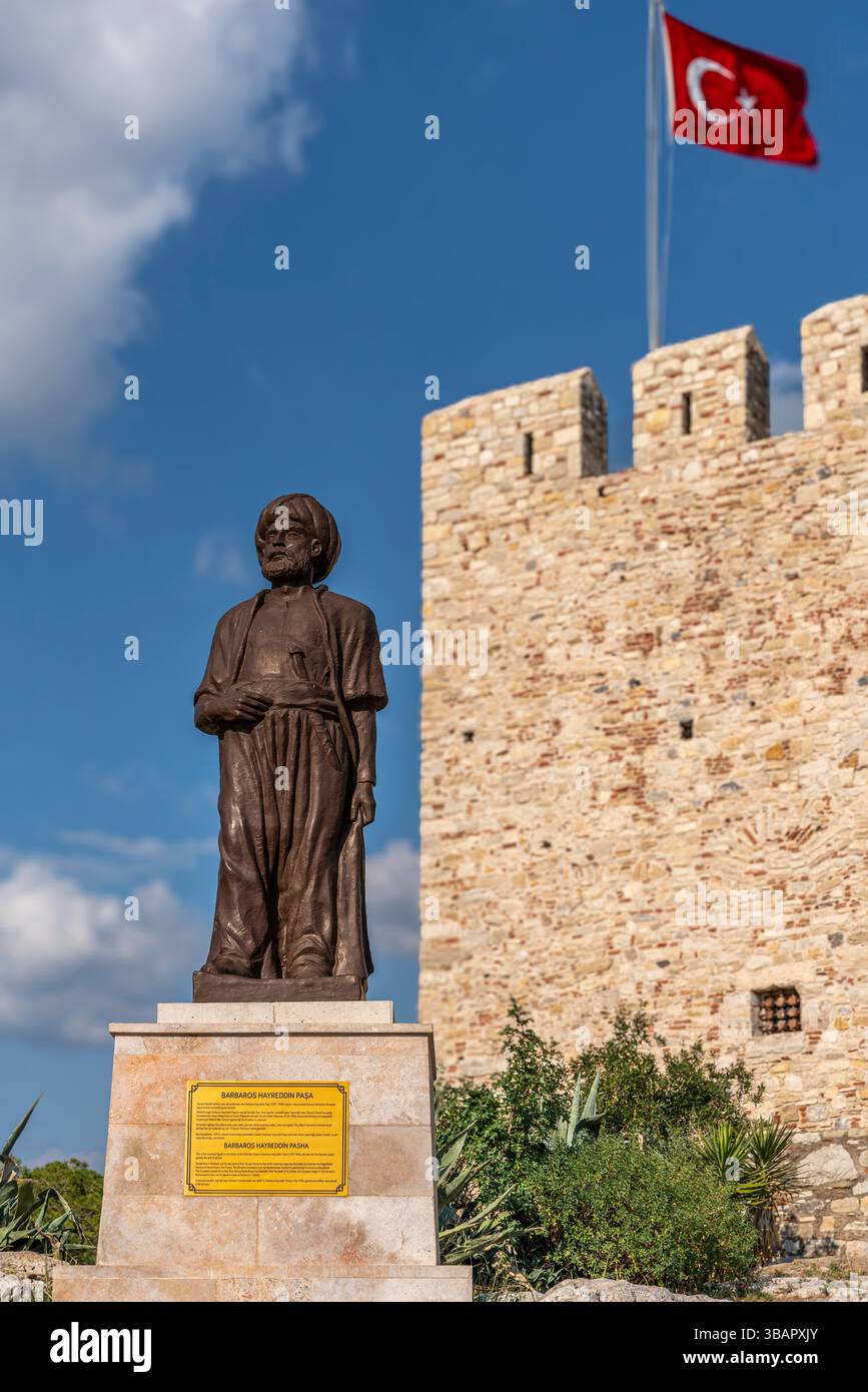 Au château de Pigeon Island à Kusadasi, la statue de Barbaros Hayreddin Pacha se dresse fièrement devant la forteresse, commémorant l’histoire navale ottomane. Banque D'Images