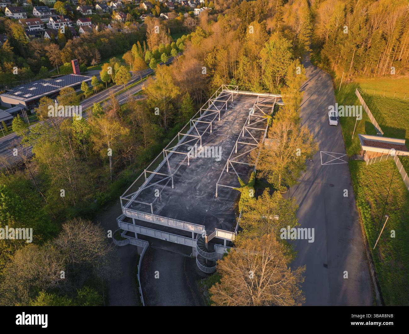 Parking vide entouré d'arbres denses et d'une route à la lumière du soir, atmosphère rurale, Nagold, district de Calw, Allemagne, Europe Banque D'Images