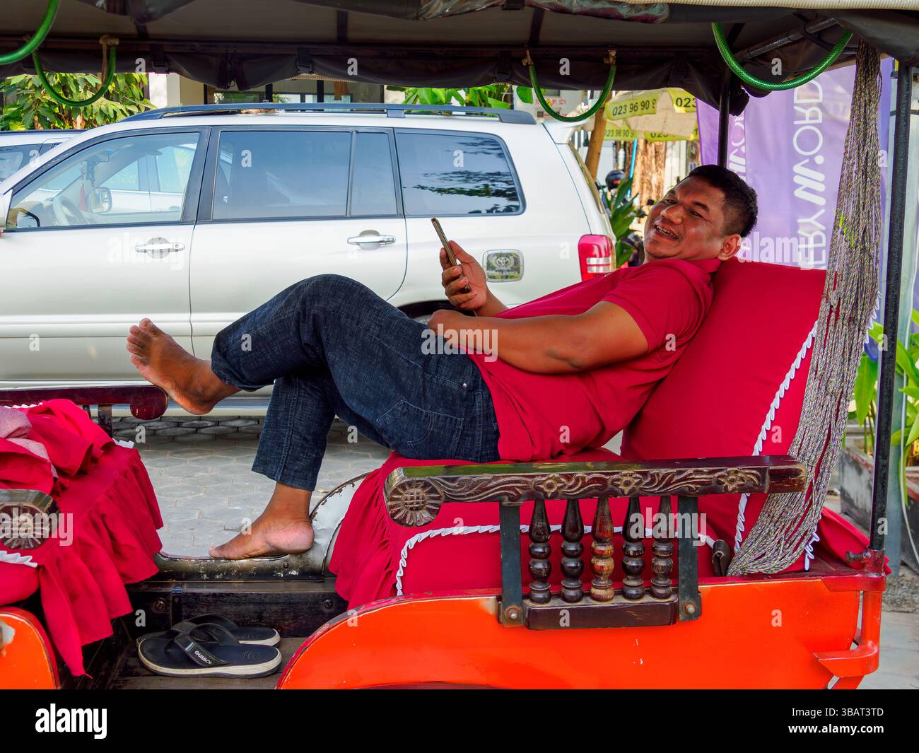 Tuk Tuk chauffeur se détend en attendant un passager, Siem Reap, Cambodge Banque D'Images