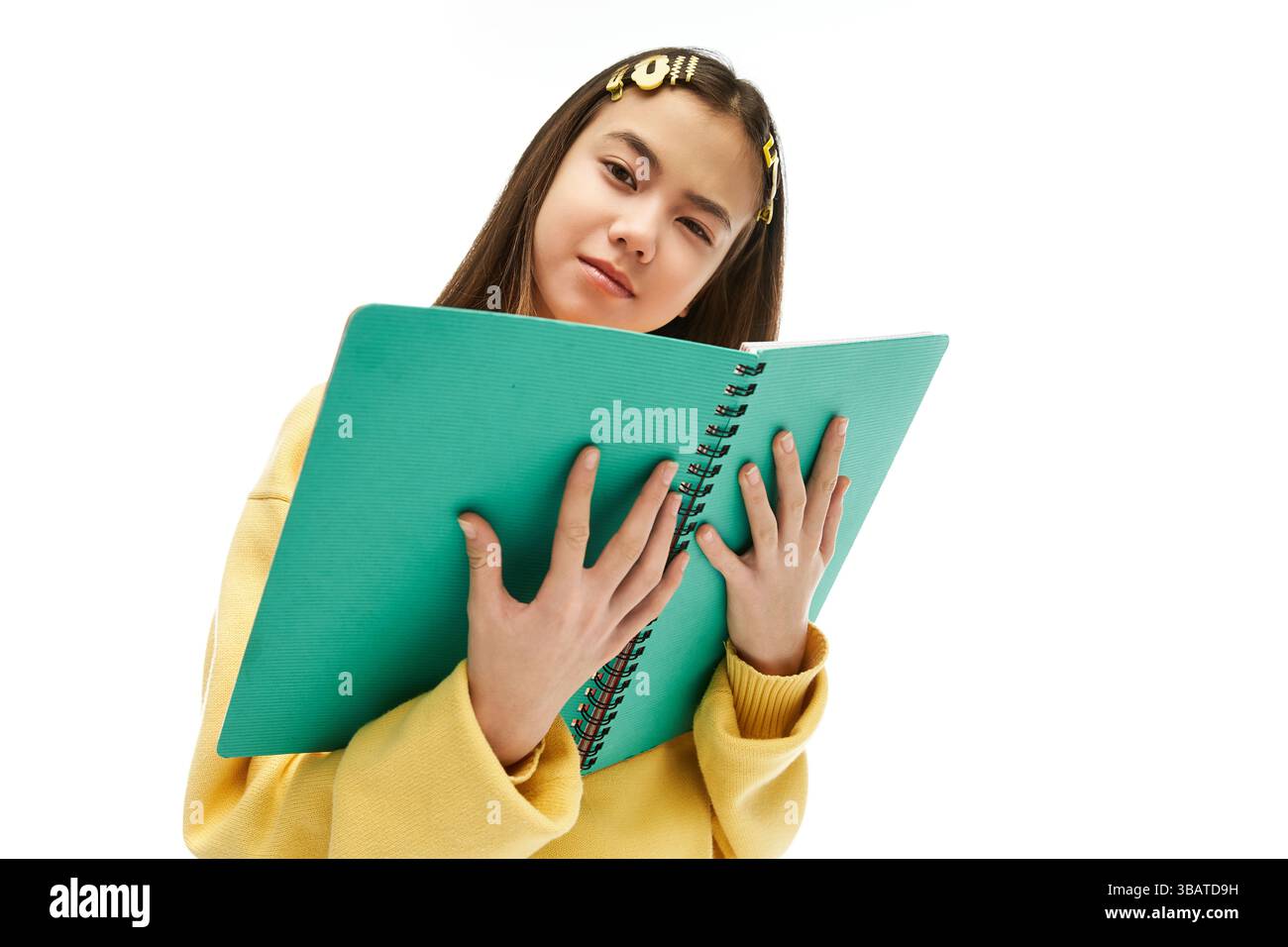 une écolière asiatique dans une tenue chic tient un cahier lumineux, mettant en valeur son style unique et sa créativité. Banque D'Images