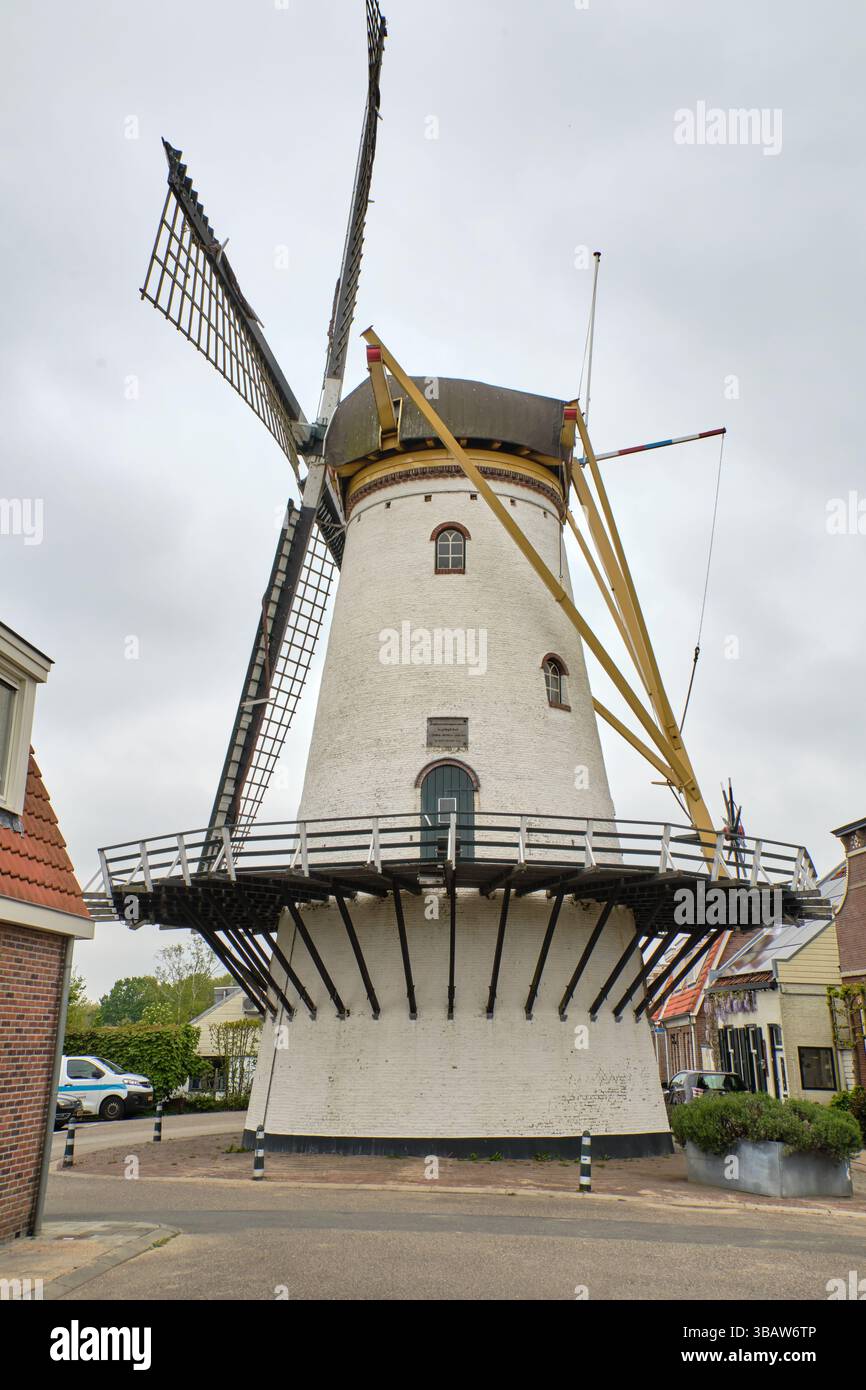 24 avril 2025 - Stellendam-pays-Bas : moulin à vent traditionnel Korenlust avec tour blanche et chapeau noir situé près du vieux port de Stellendam. Banque D'Images