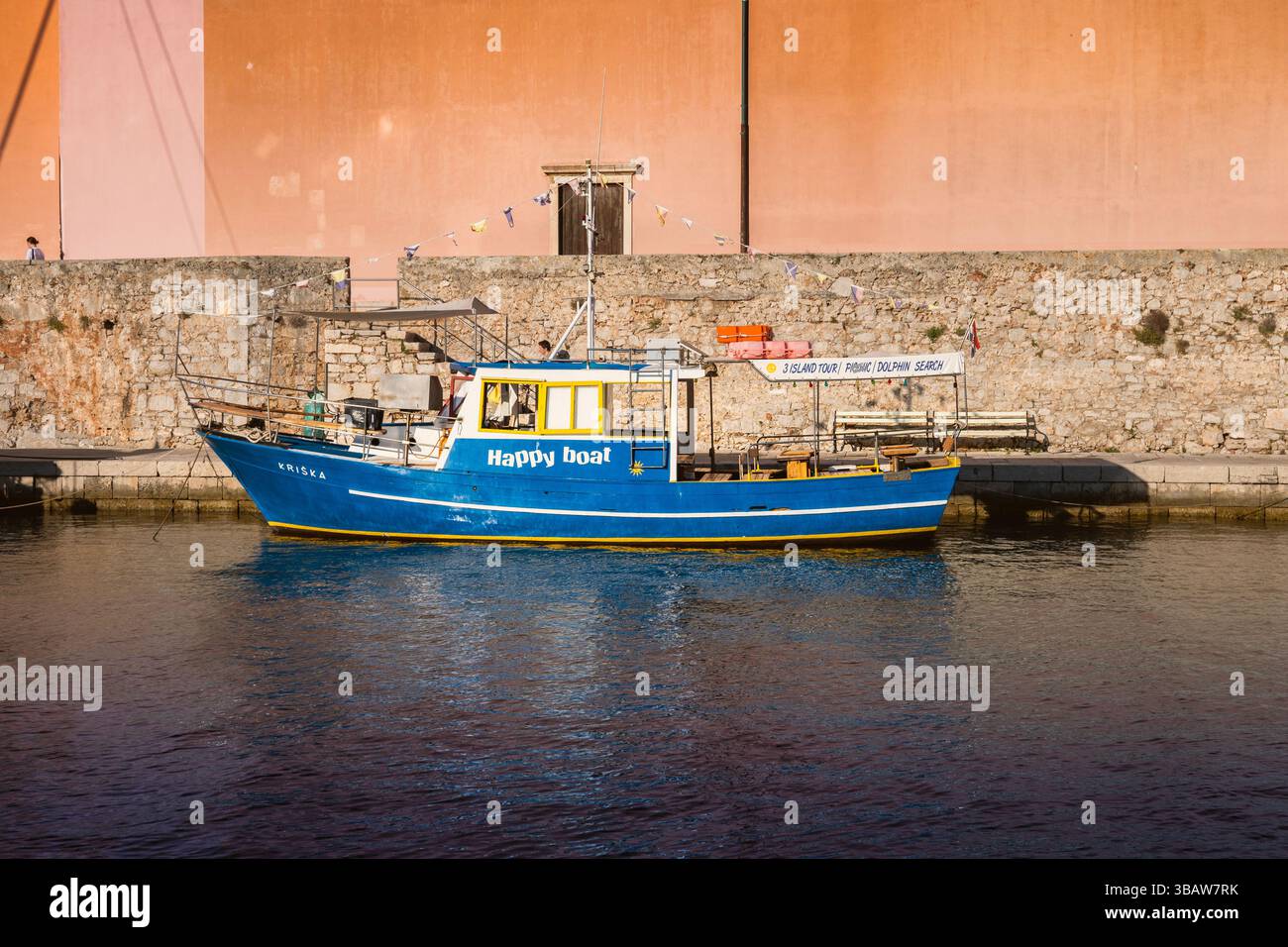 Veli Losinj, Croatie-25 juillet 2024 : joli bateau bleu, utilisé pour observer les dauphins, ancré par l'église d'Antun dans la petite ville de Veli Losinj, Banque D'Images