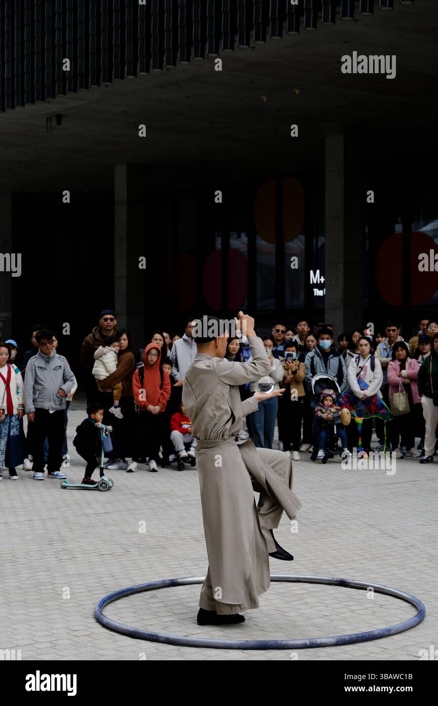 Un artiste de rue tranquille se balance à l'intérieur d'un cerceau, élevant une boule de cristal dans une danse hypnotique Banque D'Images