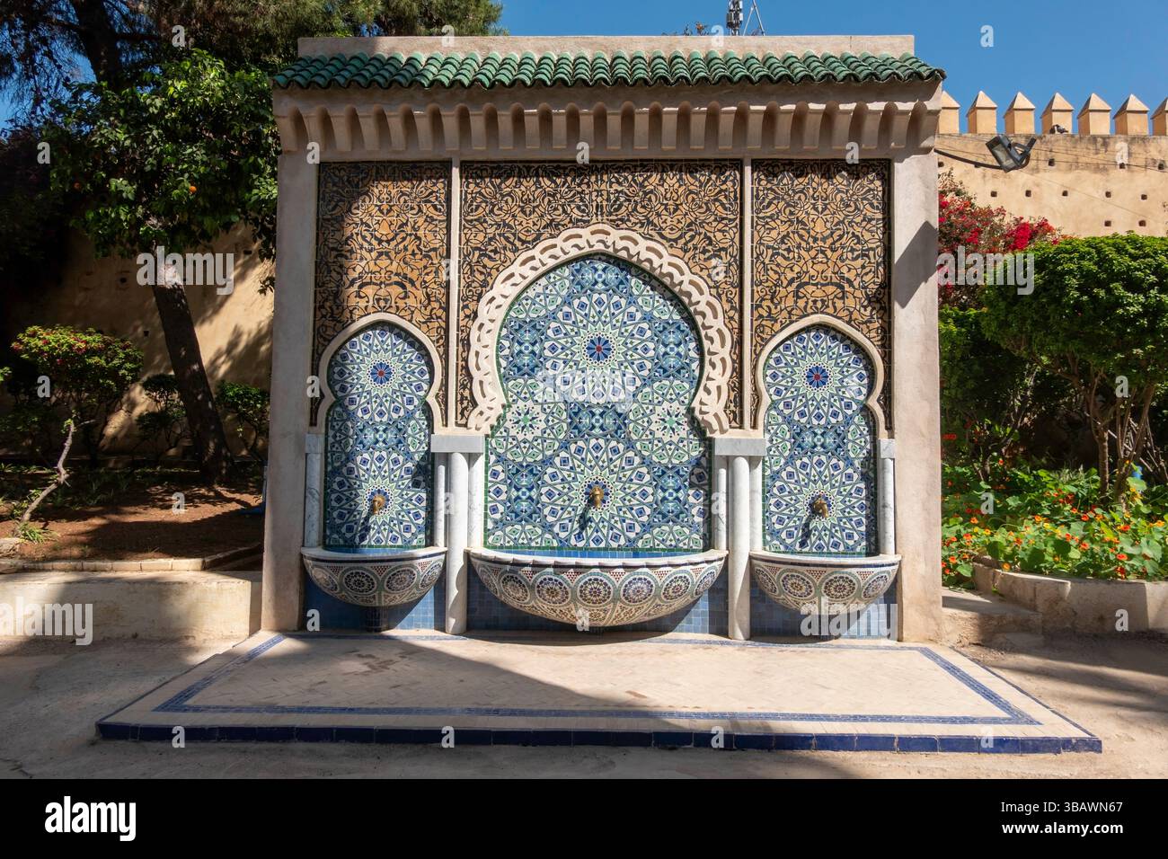Fontaine murale décorative ornée de motifs complexes en mosaïque bleue, verte et blanche. Avec ses trois becs et ses motifs floraux ornés, il incarne Banque D'Images