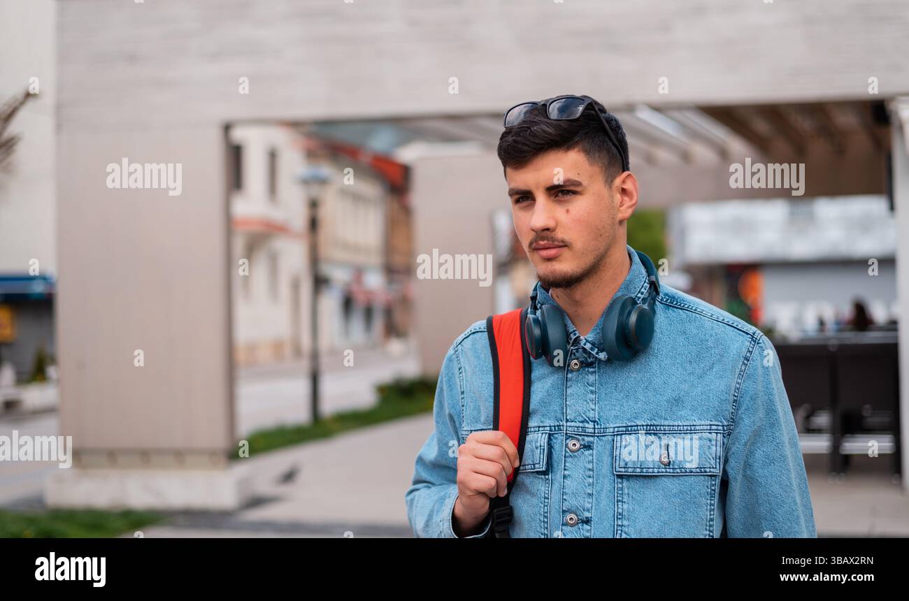 Un jeune homme élégant urbain marche dans la rue de la ville. Banque D'Images