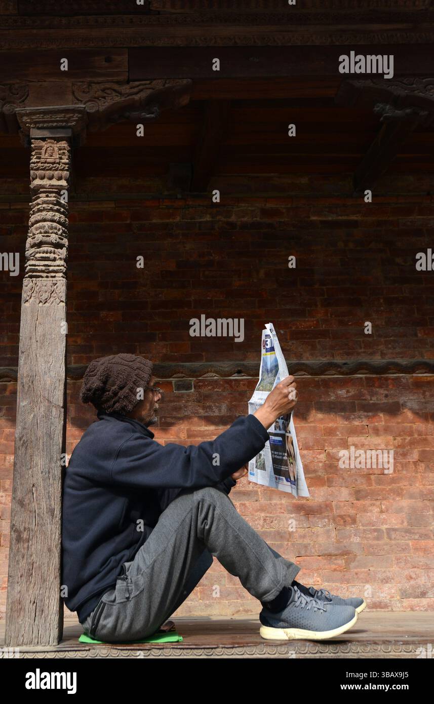 Un homme népalais lisant le journal du matin. Photo prise dans le quartier Durbar Square à Katmandou, Népal. Banque D'Images