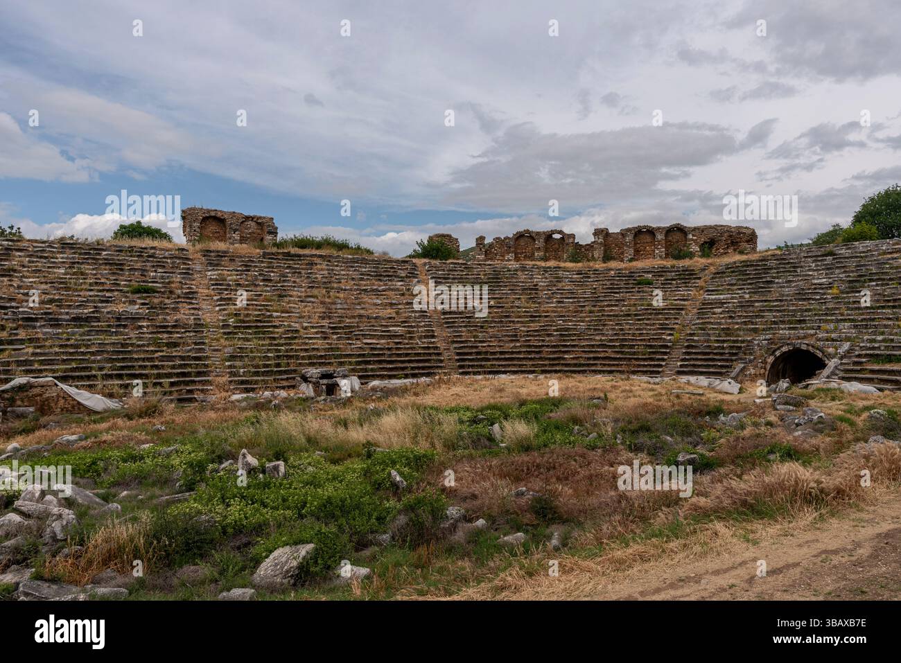 Ancien stade d'Aphrodisias, présentant des rangées de sièges voûtés et les vestiges d'une grande arène sportive, entouré de paysages accidentés. Banque D'Images