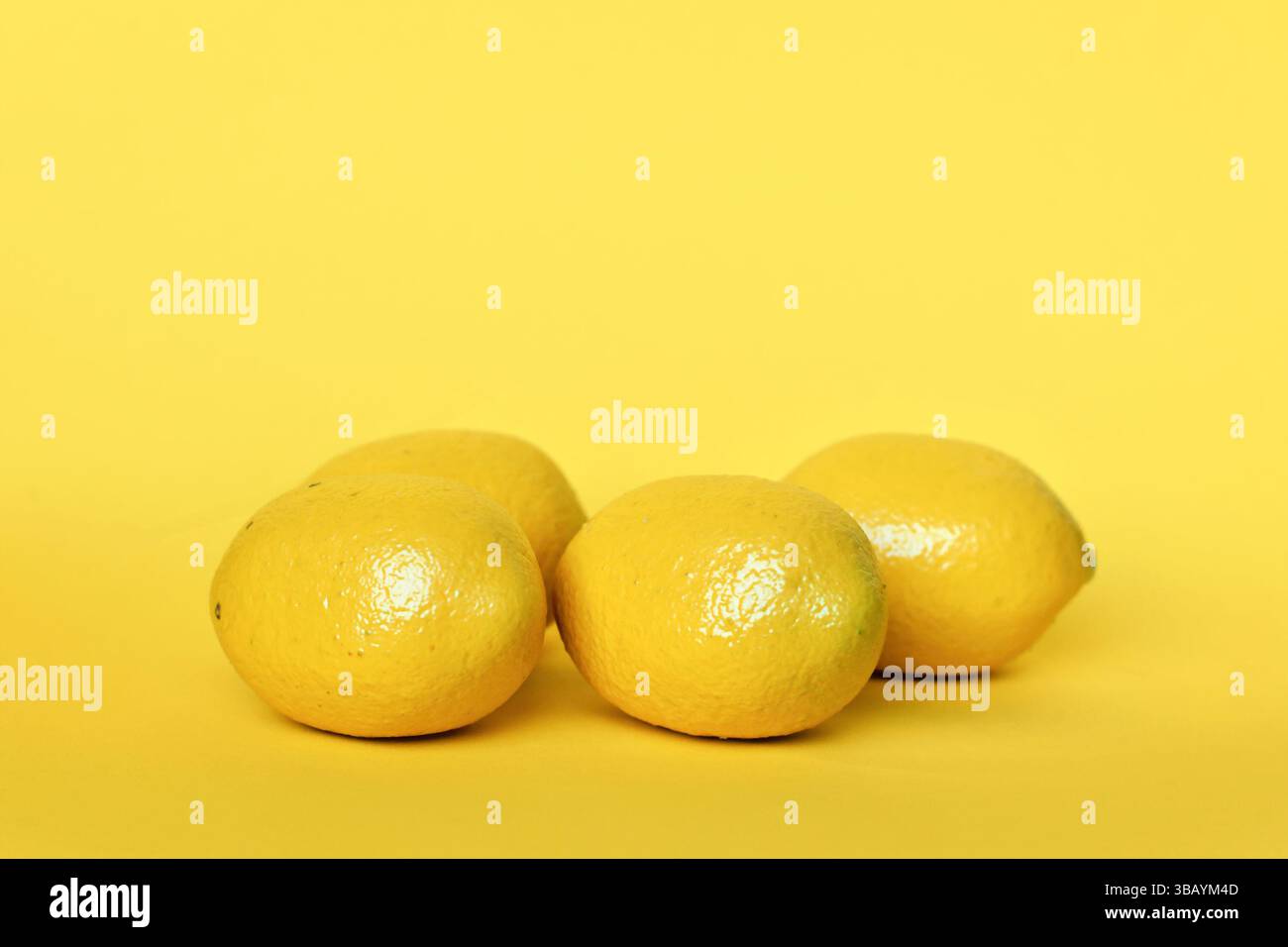 Quatre fruits de citron sur fond jaune avec espace de copie Banque D'Images