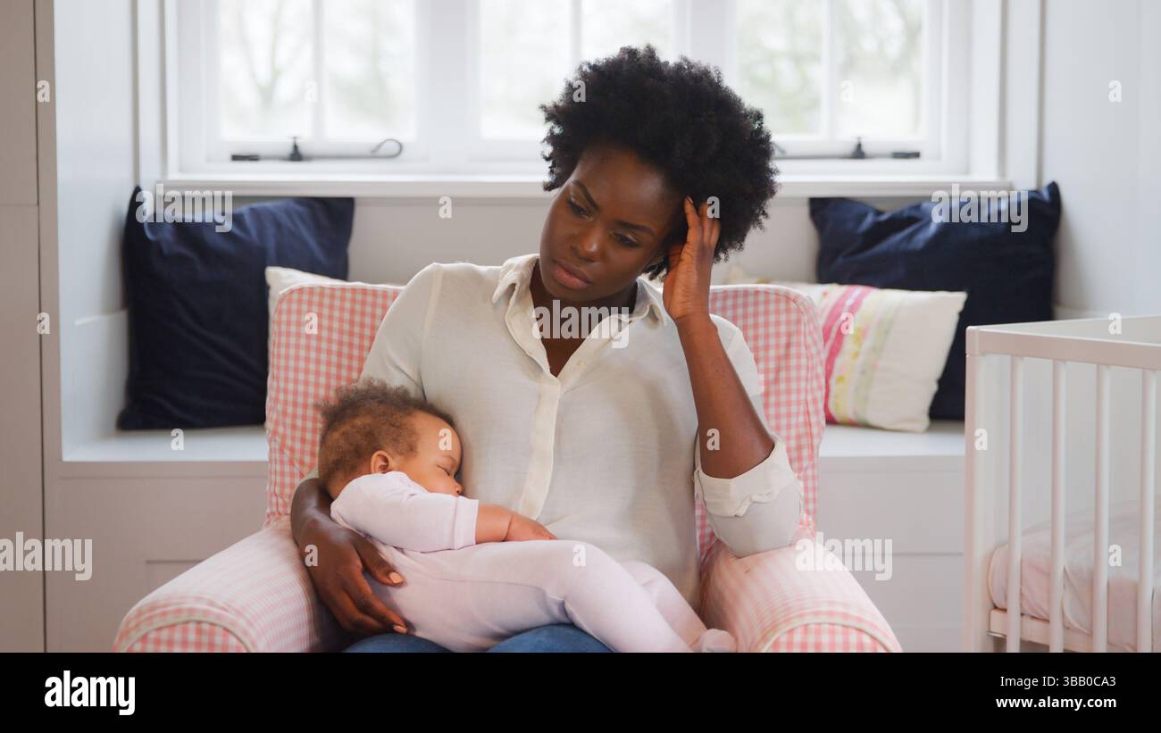 Nouvelle mère souffrant de dépression post-natale tenant la fille de bébé endormi dans la pépinière à la maison Banque D'Images