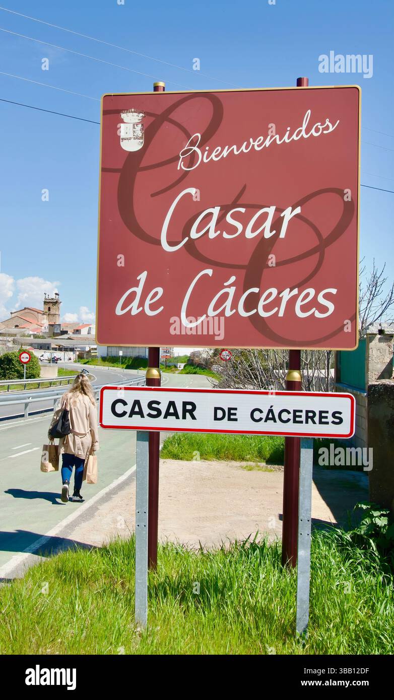 Signe de bienvenue au bord de la ville avec une femme portant des sacs à provisions pleins de fromages Torta del Casar Casar de Caceres Extremadura Espagne Europe Banque D'Images