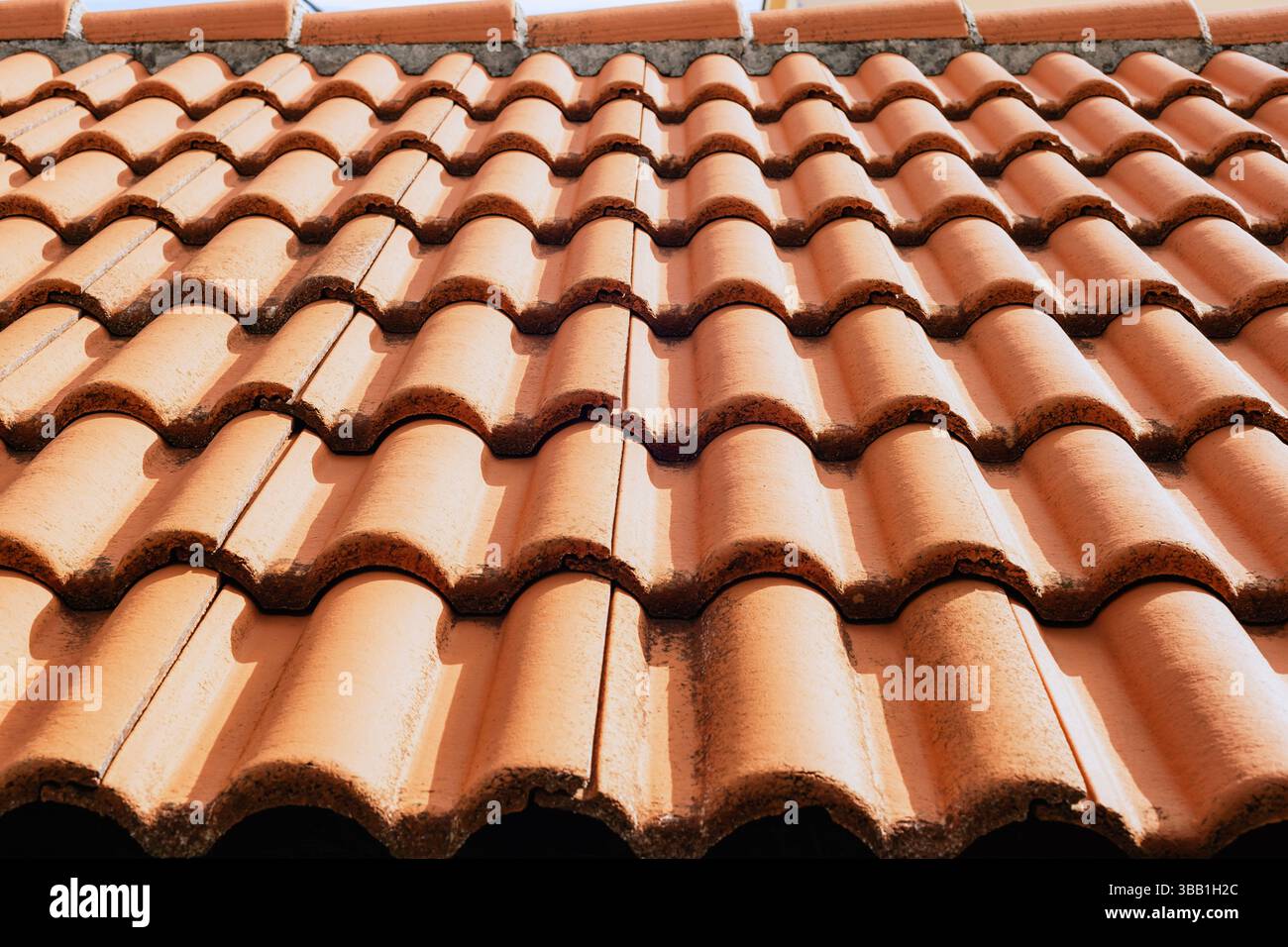 Toit en terre cuite avec tuiles de céramique texturées à la lumière du soleil. Texture, arrière-plan. Banque D'Images