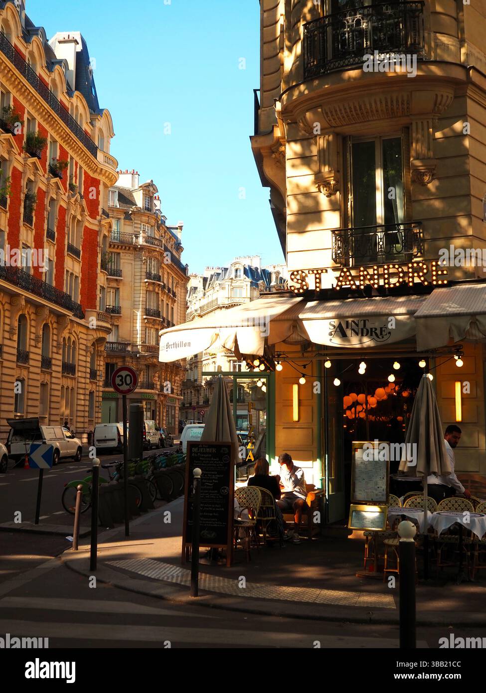 Devanture de cafés parisiens avec lumière douce le matin et bâtiments haussmanniens Banque D'Images