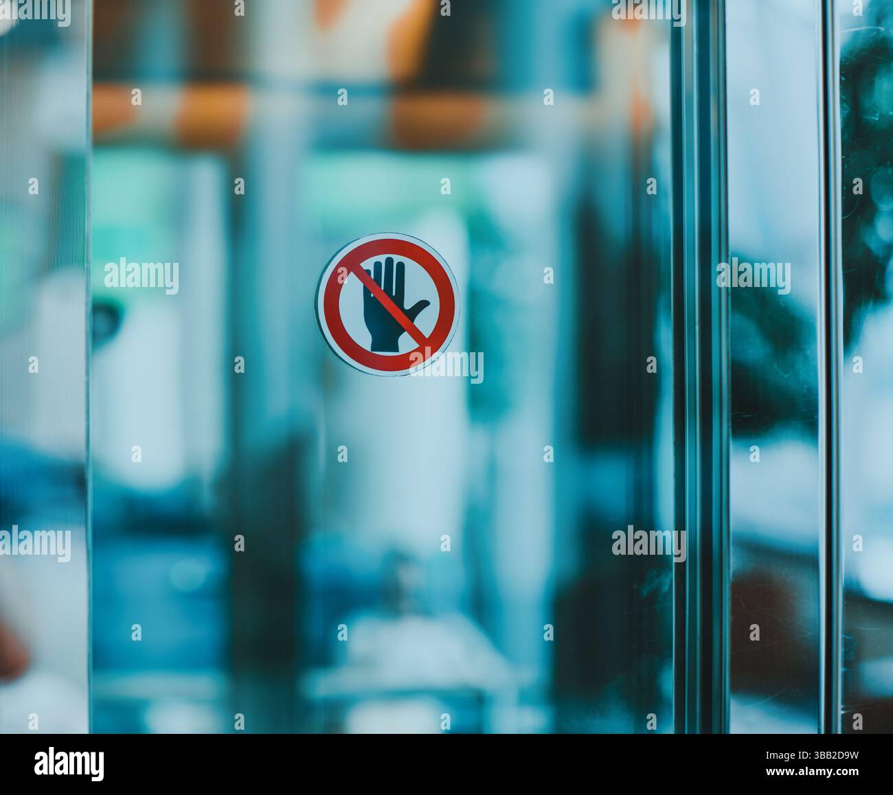 Icône d'avertissement de main d'arrêt pour ne pas toucher signe sur la porte en verre dans l'intérieur public moderne Banque D'Images