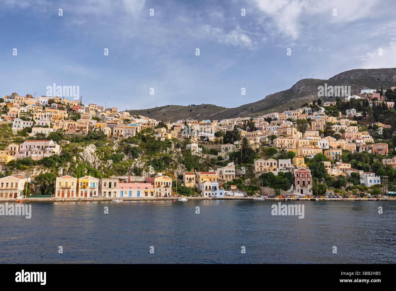 Bâtiments colorés sur une colline dans la ville idyllique de Symi au bord de la mer Égée sur l'île de Symi (Simi, Syme) en Grèce par une journée ensoleillée. Banque D'Images