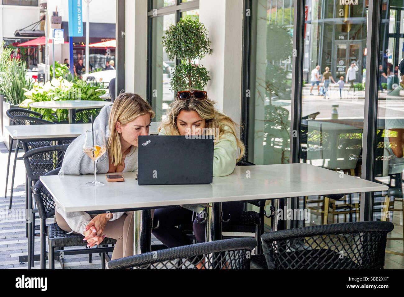 Miami Florida, Brickell Financial District, South Miami Avenue, deux jeunes femmes adultes assis table de café en plein air, travaillant sur l'ordinateur portable Lenovo ThinkPad noir, c Banque D'Images