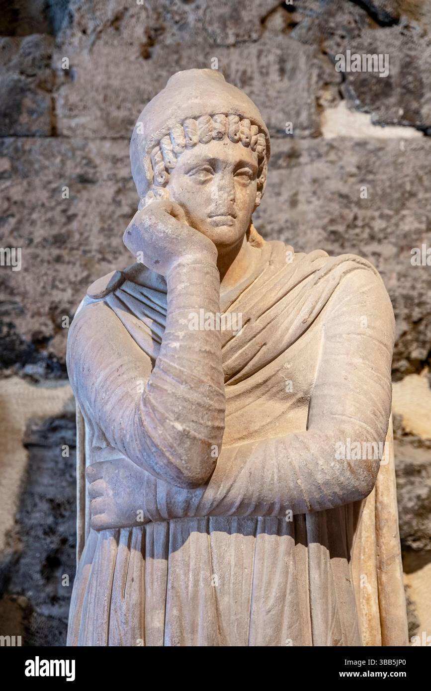 Une statue en marbre d'Attis de Hiérapolis se dresse drapée dans une robe, avec une main levée au menton et l'autre bras sur le côté. Banque D'Images