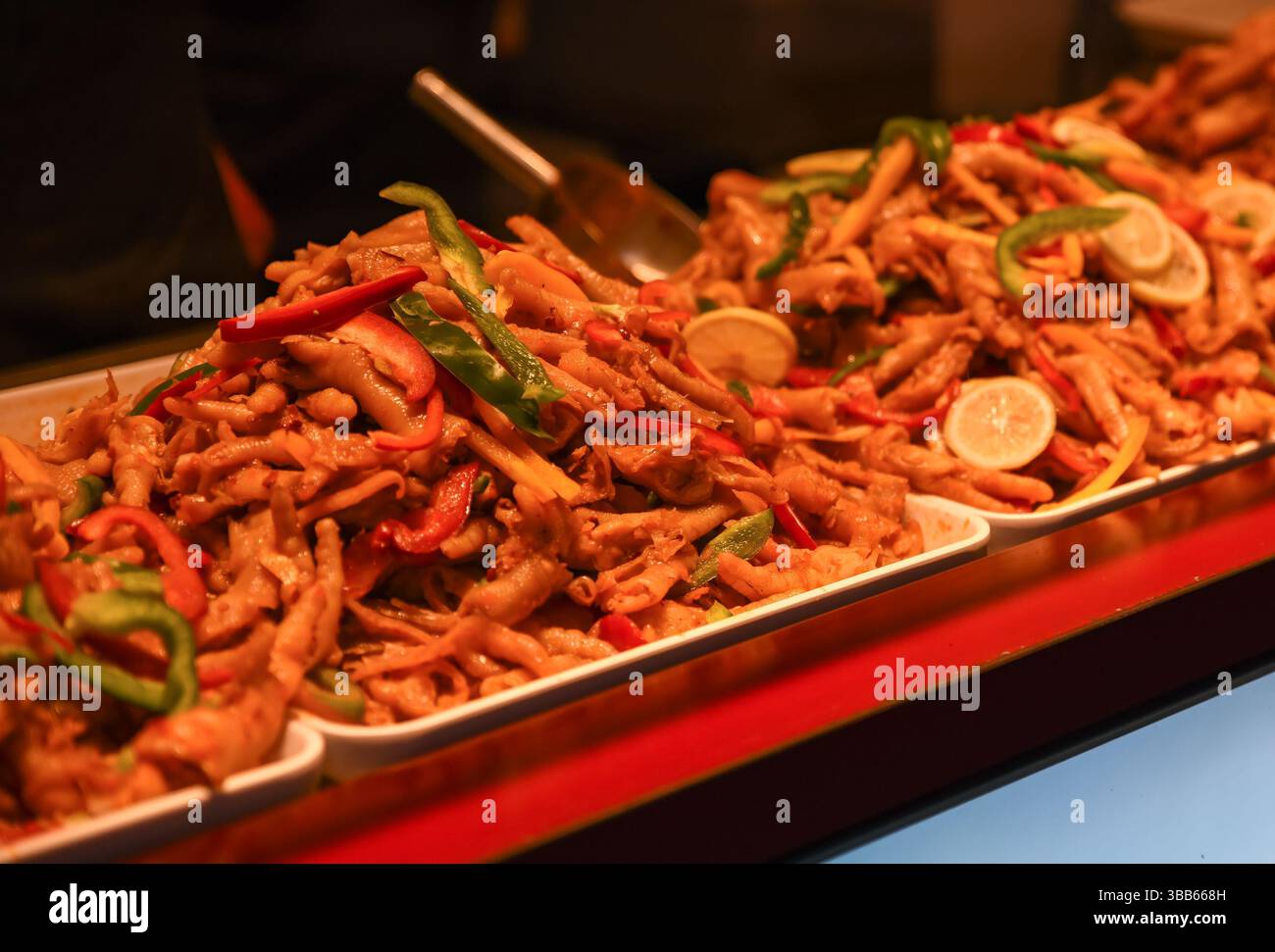 Pieds de poulet marinés épicés avec citron et piments servis dans des plateaux sur un marché de Street food de Shanghai, plat traditionnel de la cuisine chinoise. Banque D'Images