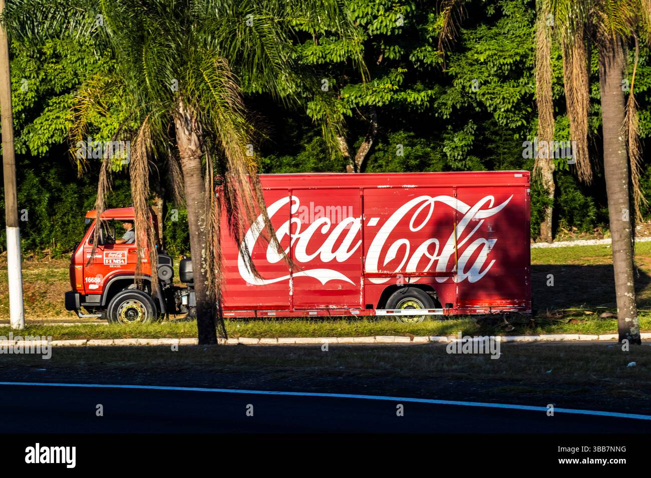 Marília, Sao Paulo, Brésil. 27 février 2025. Camion de livraison Coca-Cola FEMSA conduisant à travers une avenue dans une zone urbaine verte dans la ville de Marilia, illustr Banque D'Images