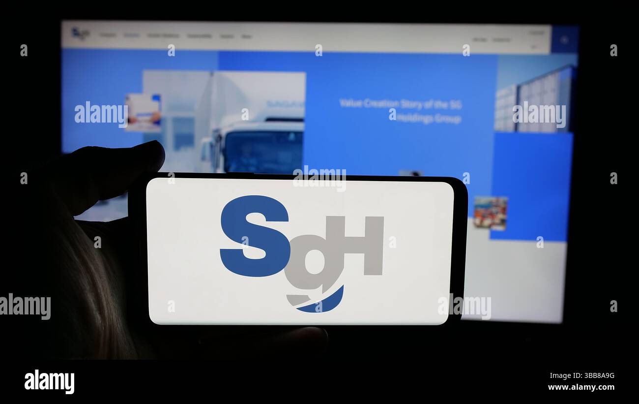 Dans cette illustration photo, une personne tient un téléphone portable avec le logo de la société de logistique SG Holdings Co. Ltd sur l'écran devant la page Web. Banque D'Images