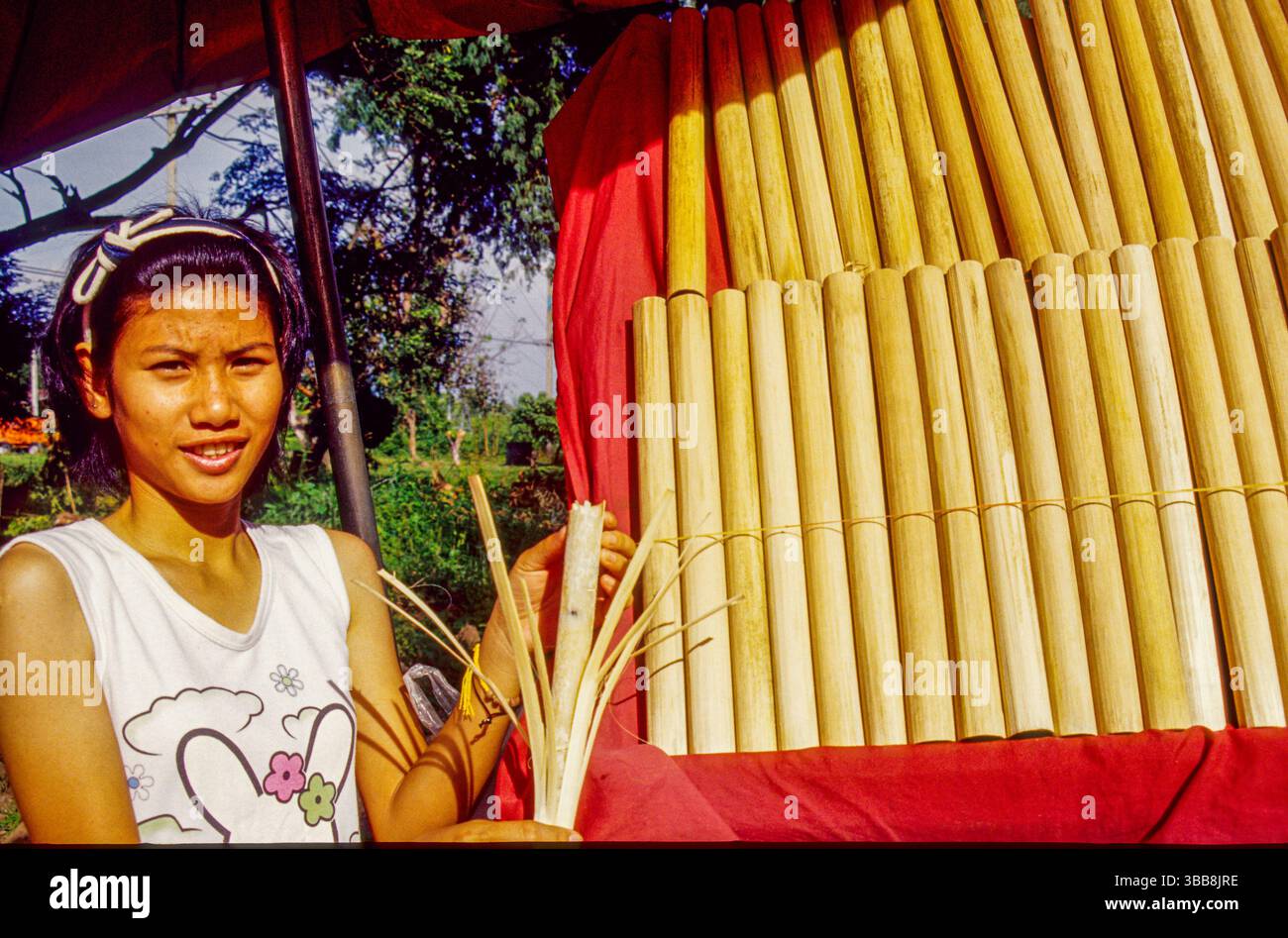 Une jeune femme sourit alors qu'elle se tient derrière une exposition de khao Lam, une collation populaire d'Asie du Sud-est. Elle tient un morceau de khao Lam, montrant comment Banque D'Images