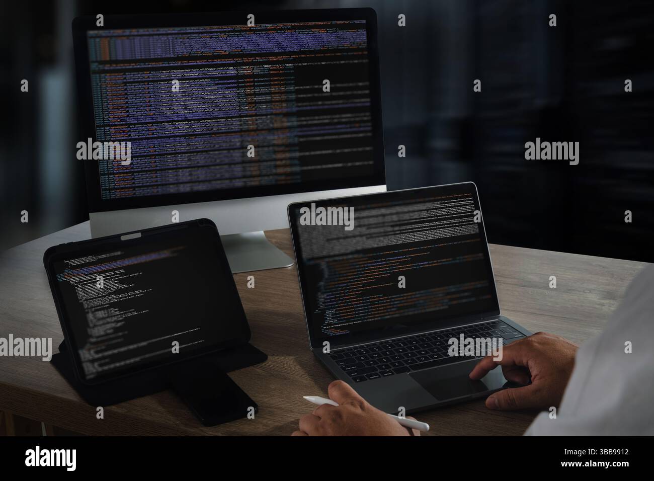 Une image de programmation de site Web montre une personne travaillant avec plusieurs dispositifs électroniques, y compris un ordinateur de bureau, un ordinateur portable et une tablette, tous affichés Banque D'Images