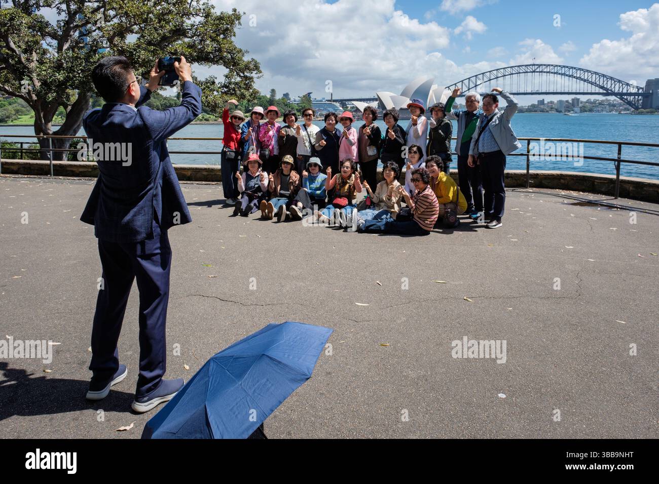 Un groupe de touristes chinois pose pour une photo de groupe avec pour toile de fond le pont du port de Sydney et l'Opéra de Sydney, Australie Banque D'Images