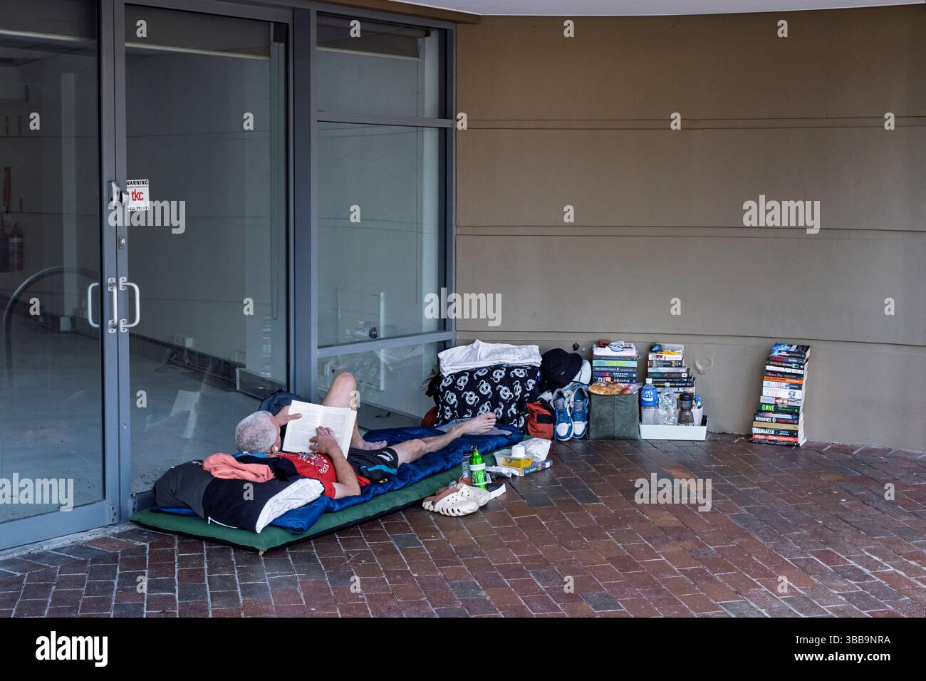 Un sans-abri lisant dans une porte, Sydney, Australie Banque D'Images