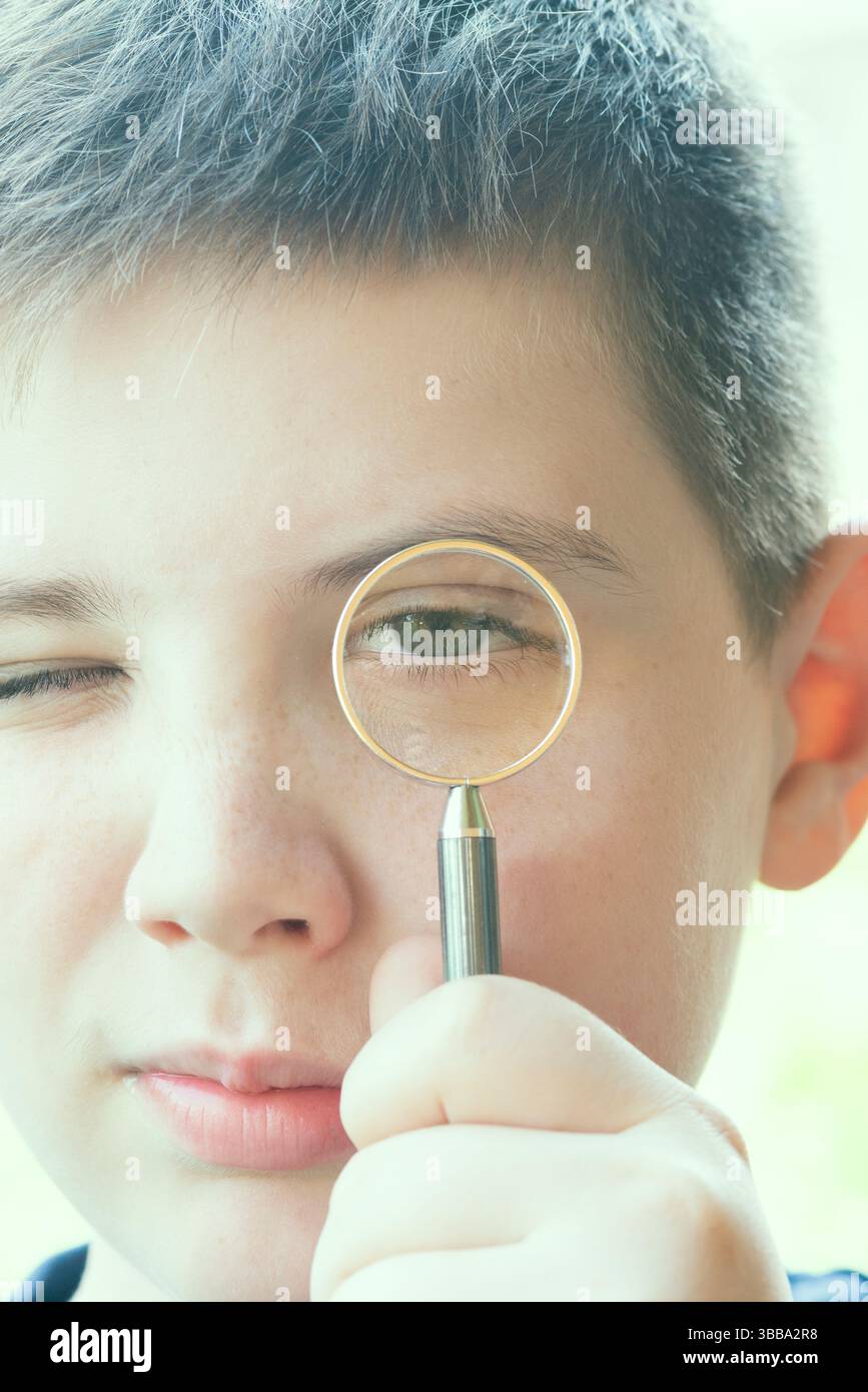 Garçon regarde à travers la loupe Banque D'Images