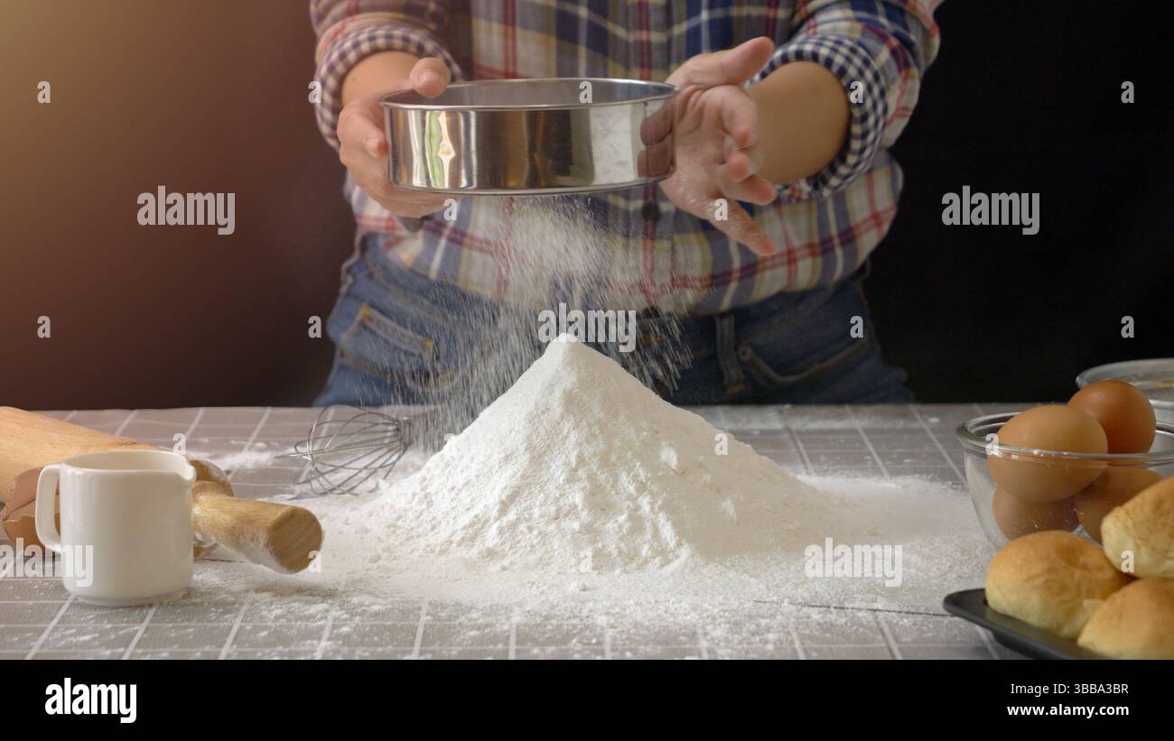 Préparation artisanale de pâte à pain. Utilisez un tamis ou une passoire pour tamiser la farine dans la pile de farine pour le pain fait à la main avec l'outil d'équipement de boulangerie Banque D'Images