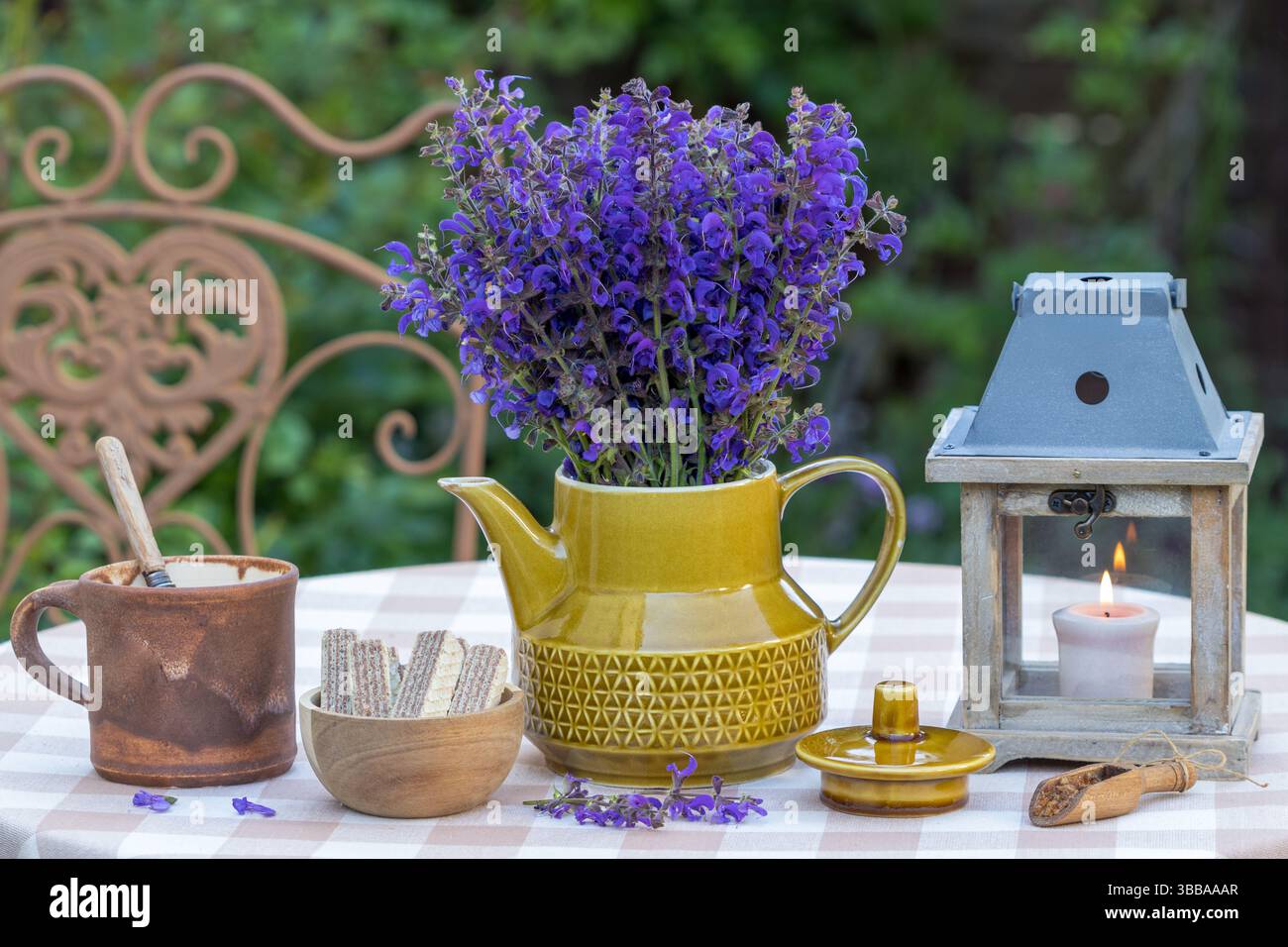 arrangement de table avec bouquet de sauge de prairie, pâtisserie, tasse de café et une lanterne Banque D'Images
