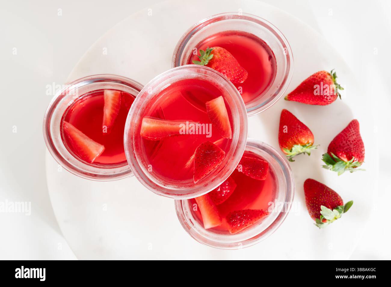 Dessert en gélatine de fraise dans des bols en verre, gros plan sur une table blanche directement d'en haut Banque D'Images Dessert en gélatine de fraise dans des bols en verre, gros plan sur une table blanche directement d'en haut Banque D'Images