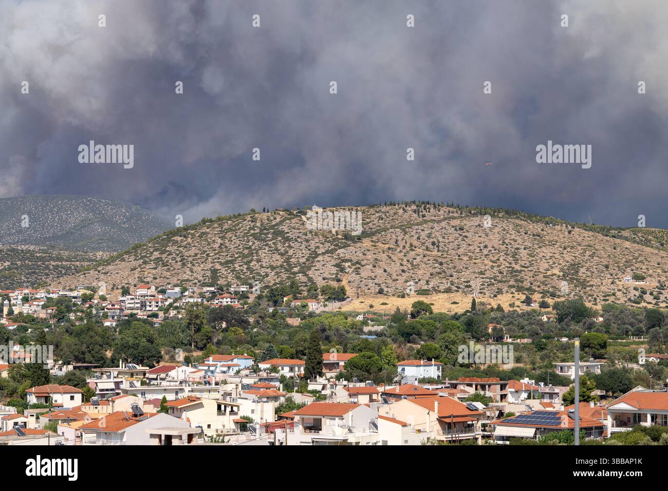 La fumée dense des feux de forêt s'élève derrière une ville de banlieue, soulignant la menace croissante de catastrophes naturelles et de crises liées au climat dans les zones résidentielles Banque D'Images