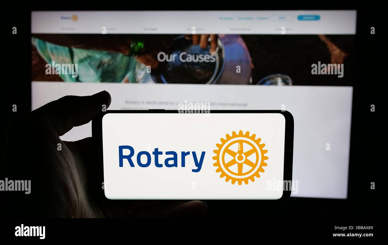 Stuttgart, Allemagne - 12-30-2024 : Personne tenant un téléphone portable avec le logo du club de service Rotary International sur l'écran devant la page web. Banque D'Images