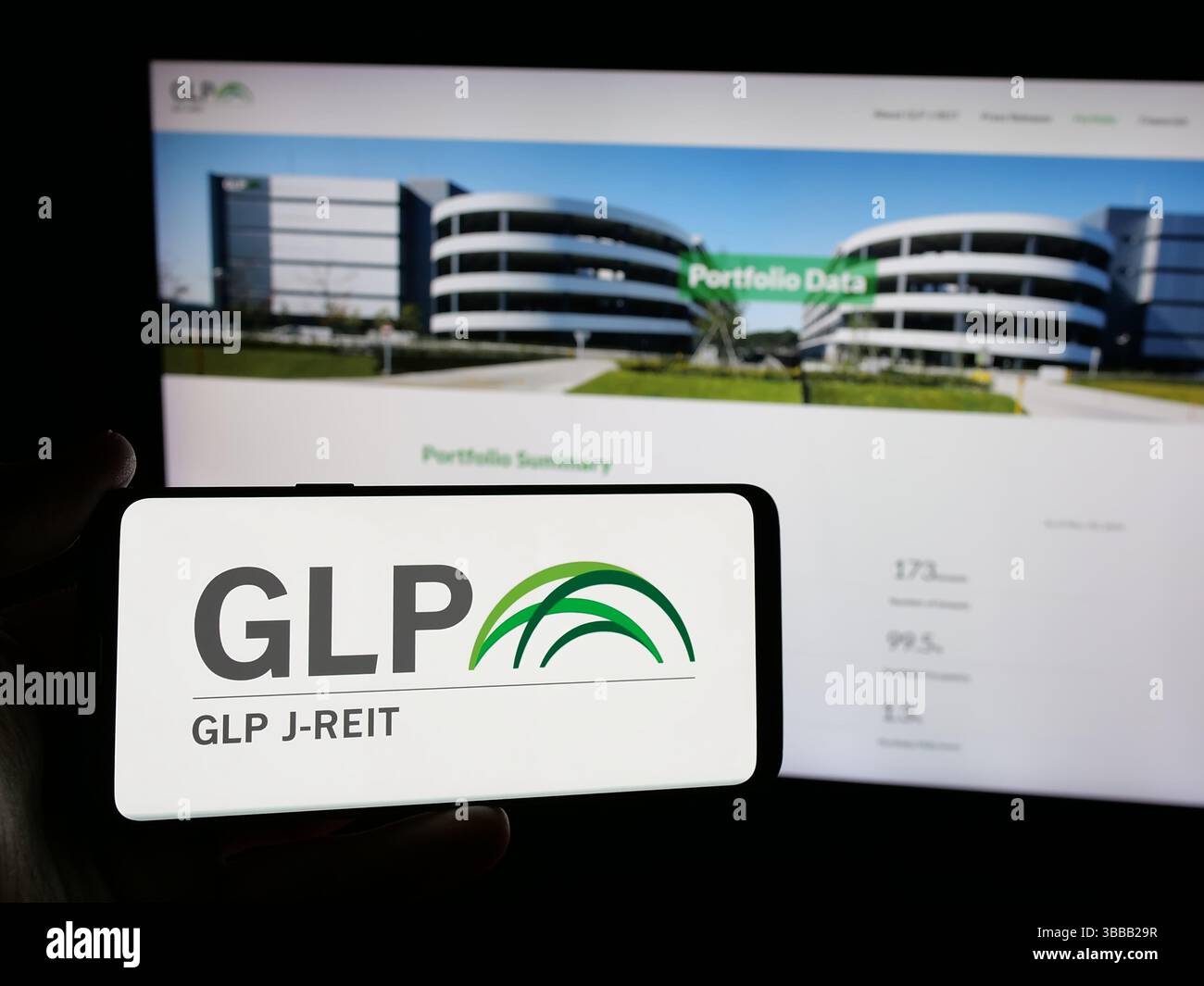 Stuttgart, Allemagne - 01-02-2024 : personne tenant un smartphone avec le logo de la société immobilière japonaise GLP J-REIT sur l'écran devant le site. Banque D'Images