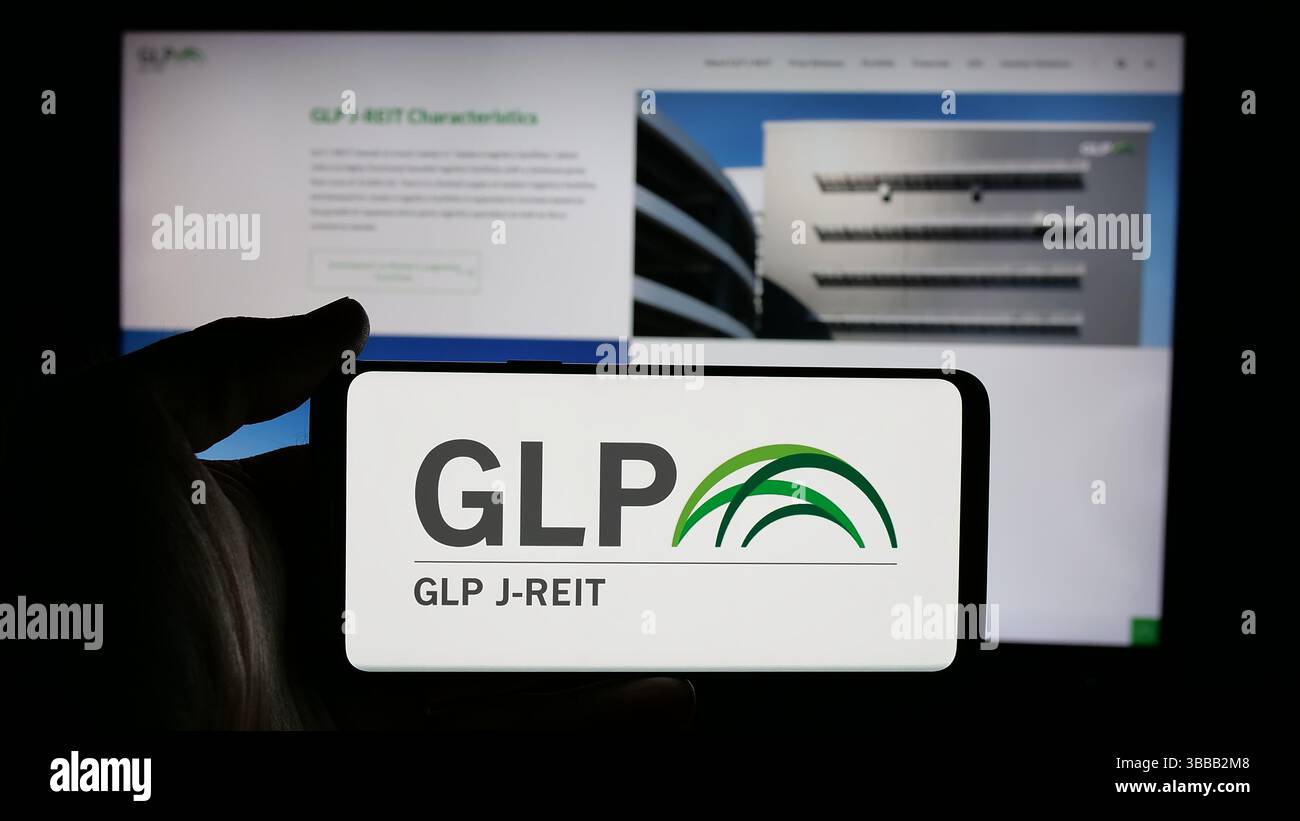 Stuttgart, Allemagne - 01-02-2024 : personne tenant un téléphone portable avec le logo de la société immobilière japonaise GLP J-REIT sur l'écran devant la page Web de l'entreprise. Banque D'Images