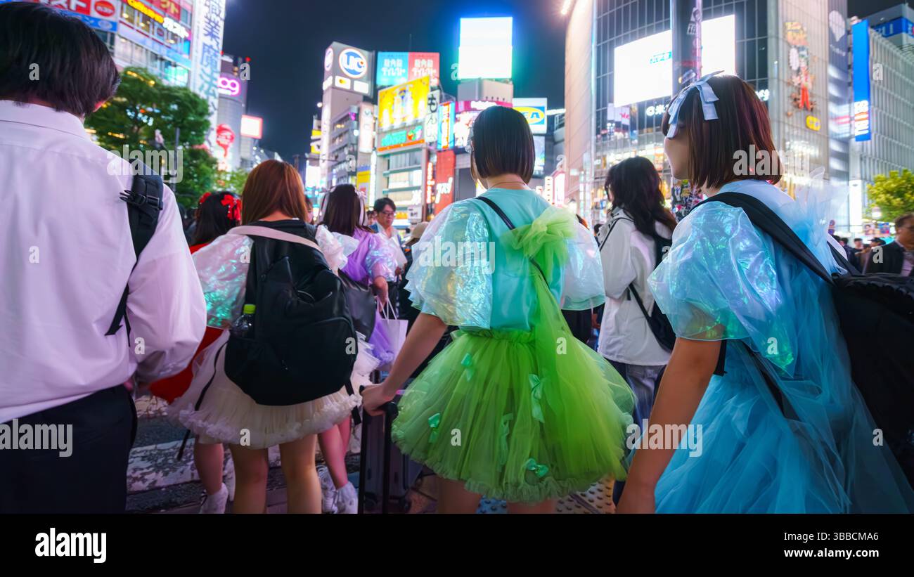 Tokyo, Japon - Sep 30 2024, vue panoramique de filles en robes colorées marchant à travers la foule à Shibuya Crossing avec des panneaux d'affichage illuminés sur b Banque D'Images
